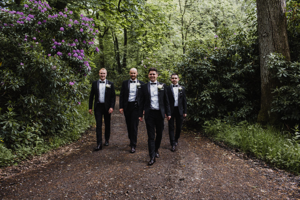 groom and his ushers in black tie walk through the woods in Scotland