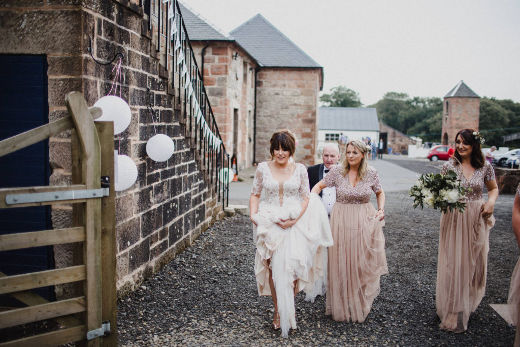 bride and her bridesmaids walk to the wedding ceremony at Boswell's Coach House Ayrshire
