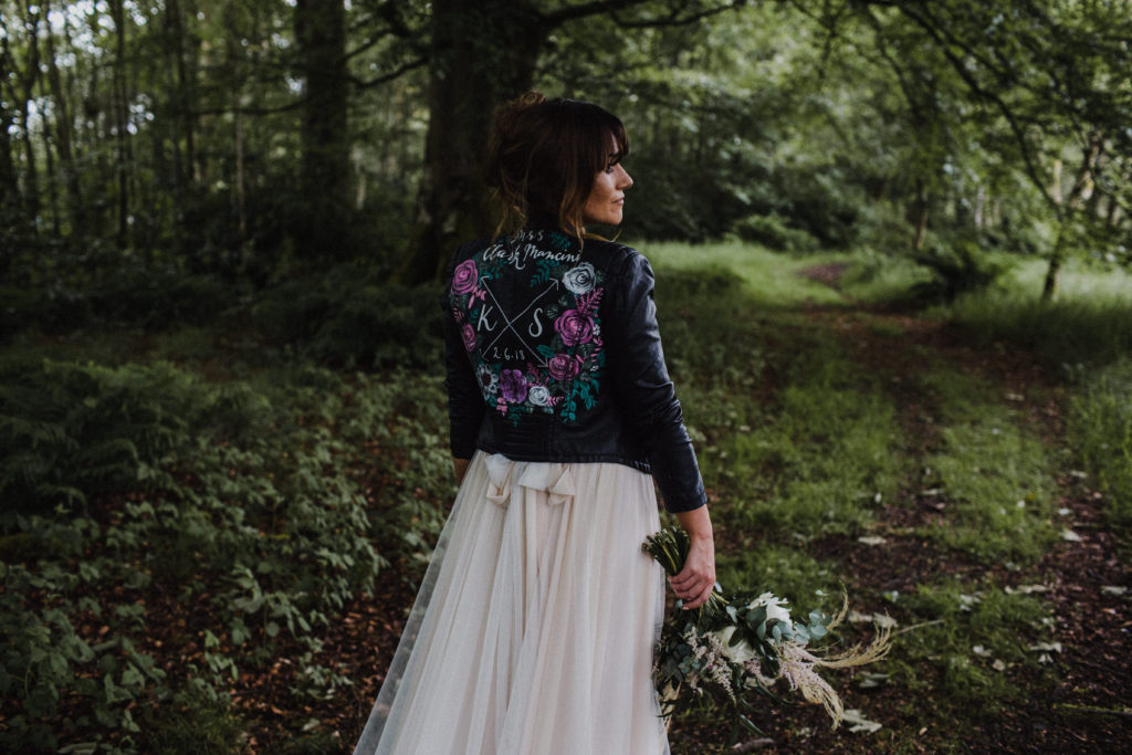 bride wearing embellished leather jacket looking into the woods at Boswell's Coach House Ayrshire