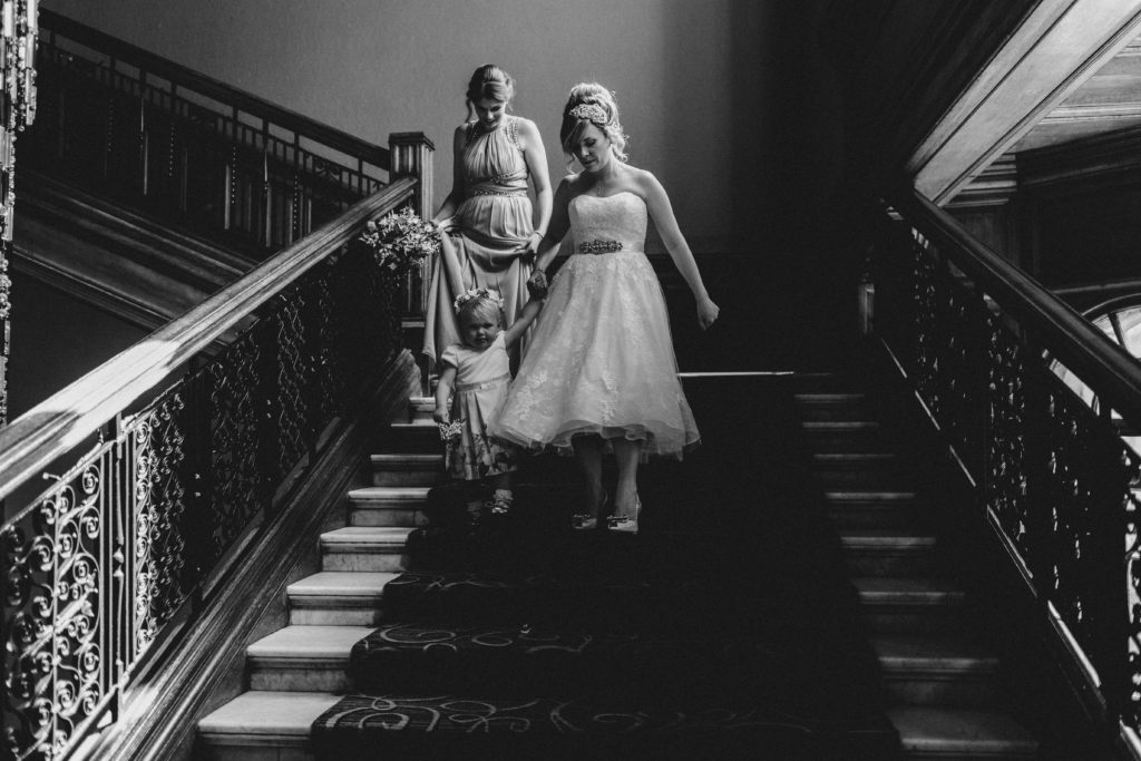 bride bridesmaid and flower girl walking down stairs at Grand Central hotel Glasgow to the wedding ceremony