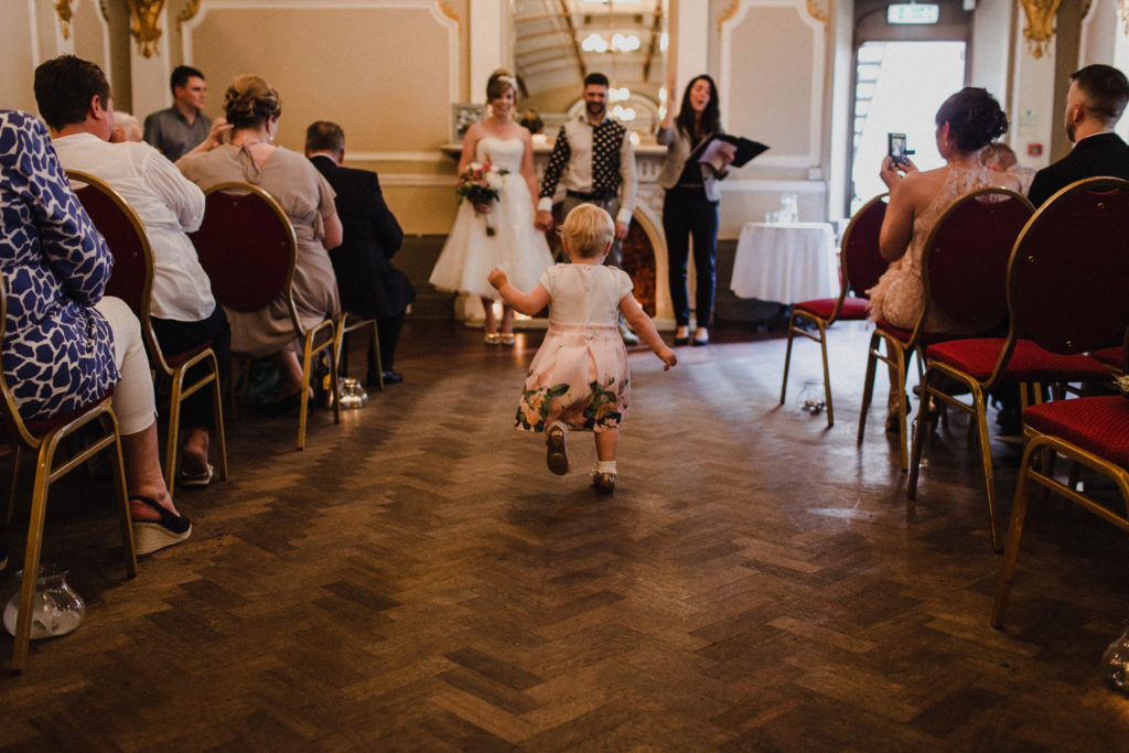 couple's young daughter runs up the aisle to them at their wedding at Sloan's bar Glasgow