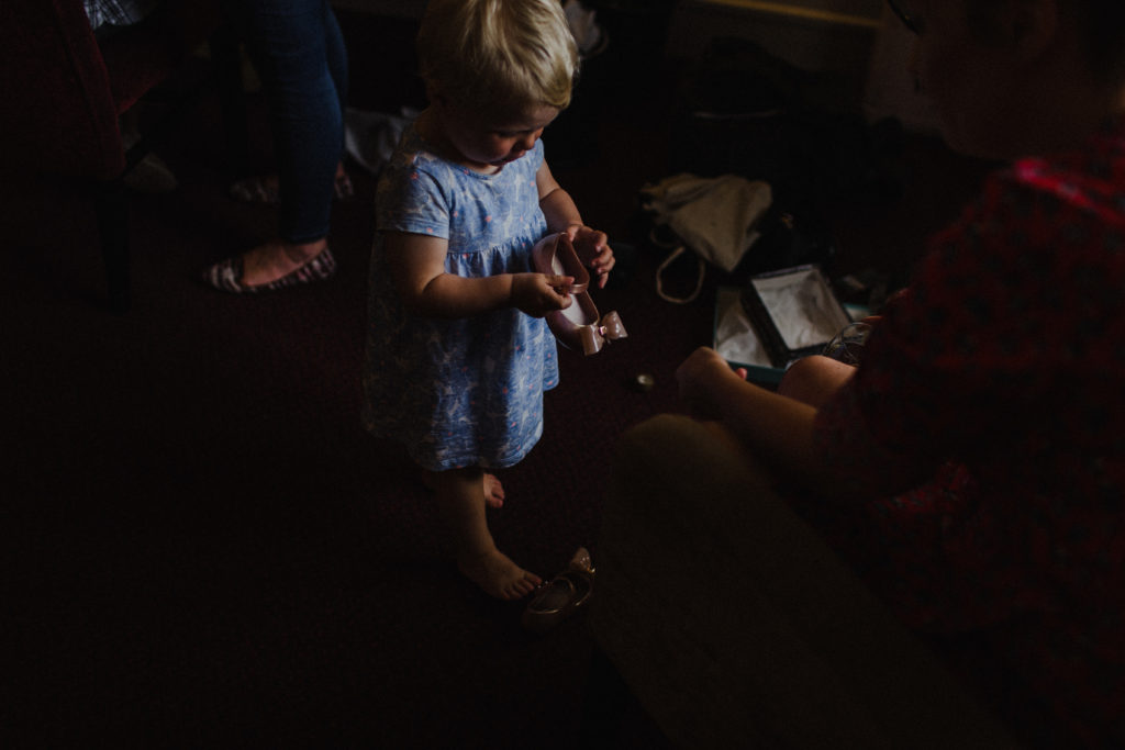 flower girl looking at her shoes getting ready for the wedding at Grand Central Hotel Glasgow