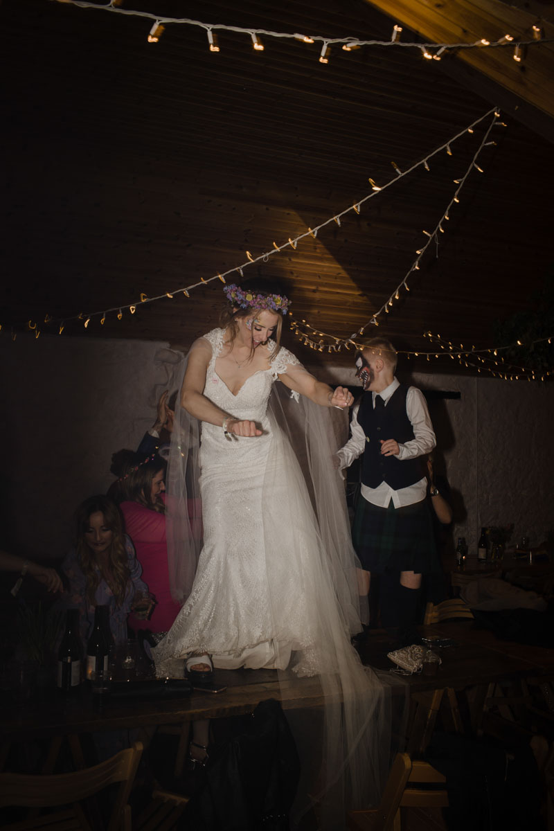 Bride dancing on table at wedding