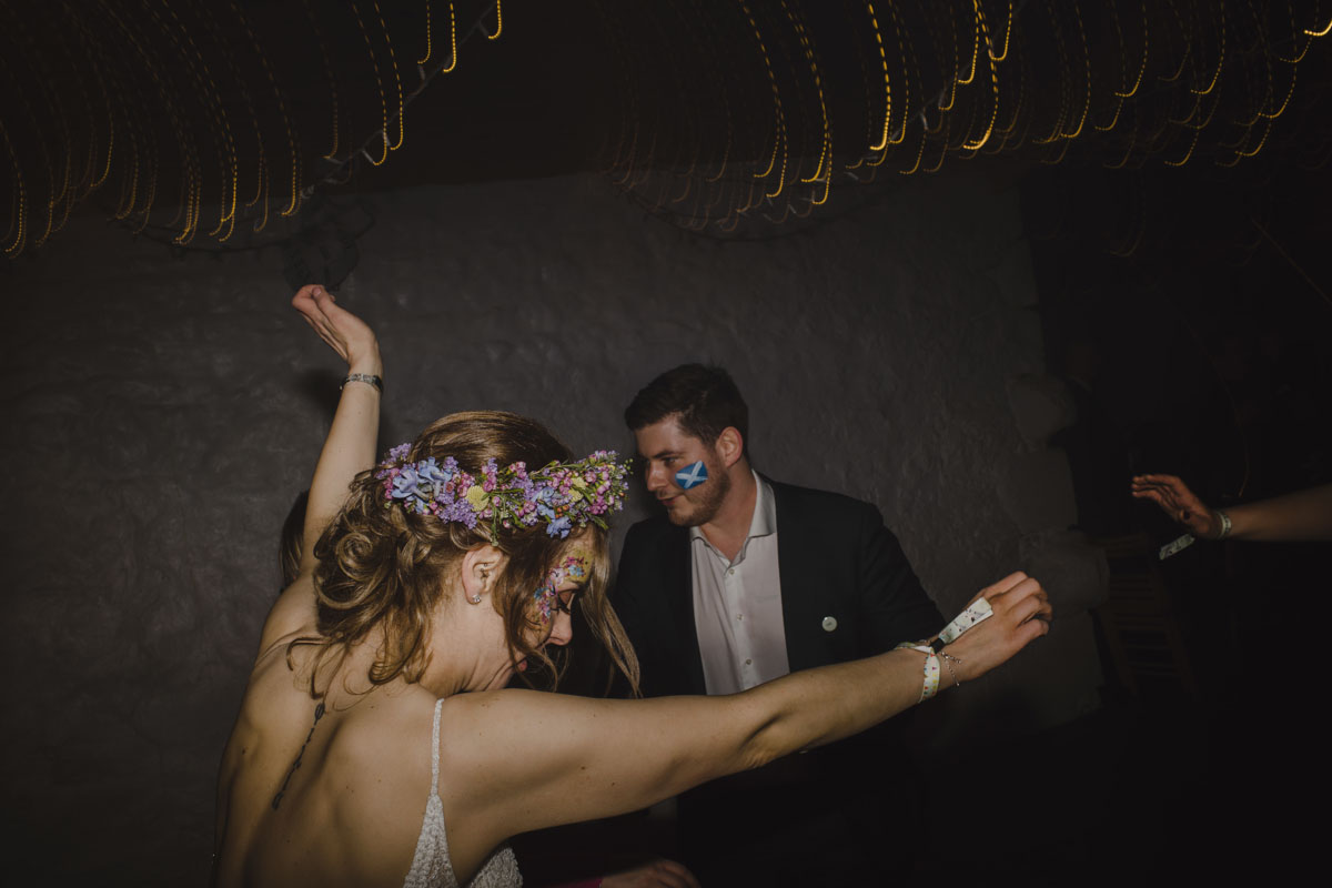 Bride in flower crown dances with arms in the air