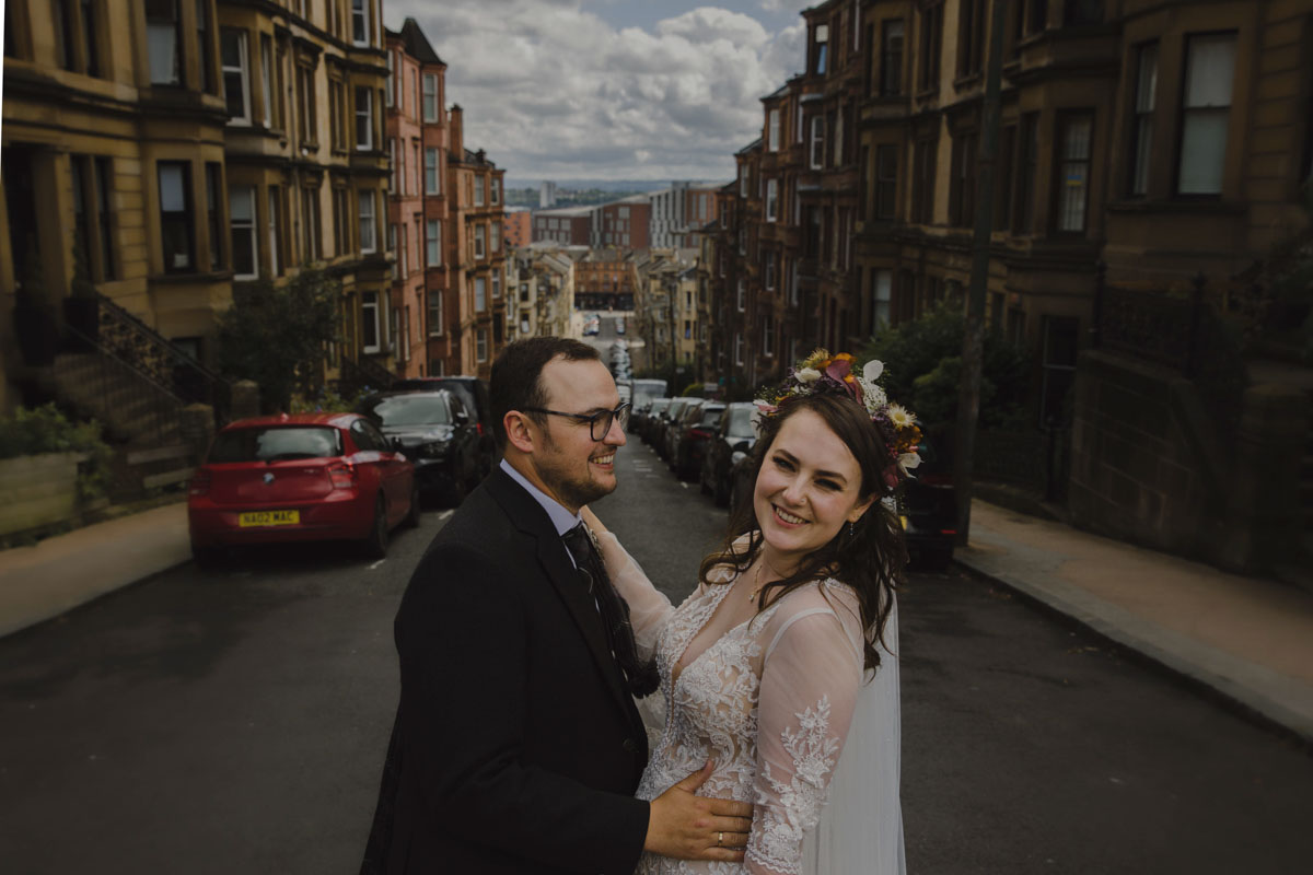 Bride and groom post outside Glasgow tenements during their wedding day at Cottiers