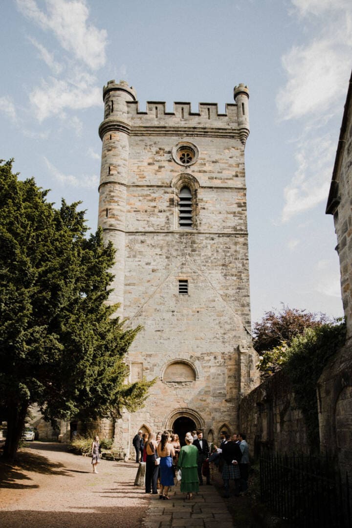 Historic Culross Abbey tower with wedding guests outside, Scottish wedding venue.