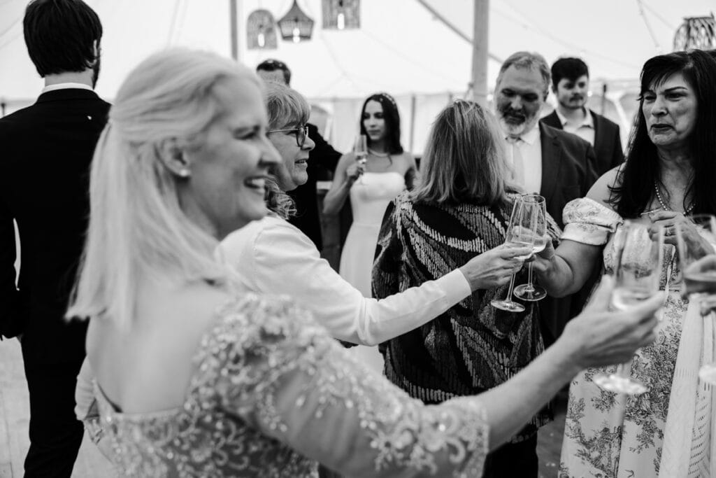 Celebrating at a wedding reception with guests raising glasses in a joyful toast, capturing candid,.