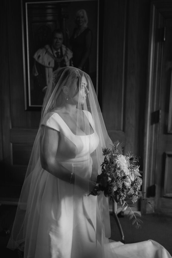Elegant bride with veil holding a bouquet at a Scottish wedding venue.