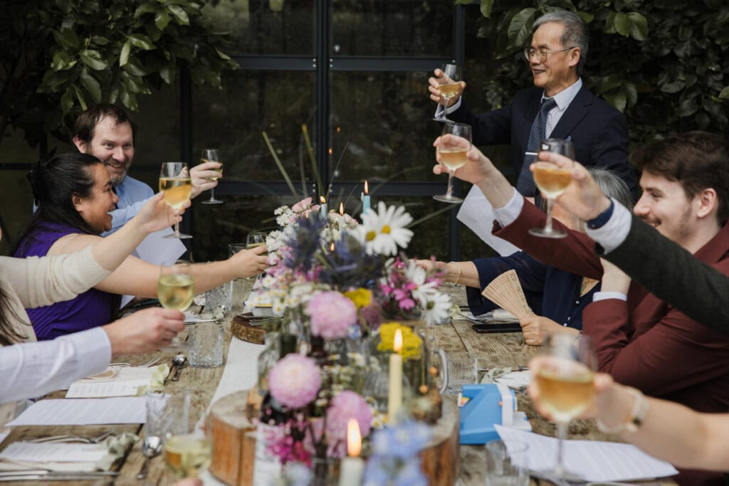 Celebratory toast at a wedding reception with friends and family in the glasshouse at Kilmartin Castle.