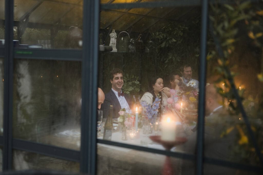 Intimate wedding celebration captured through a windows of the glasshouse at Kilmartin Castle.
