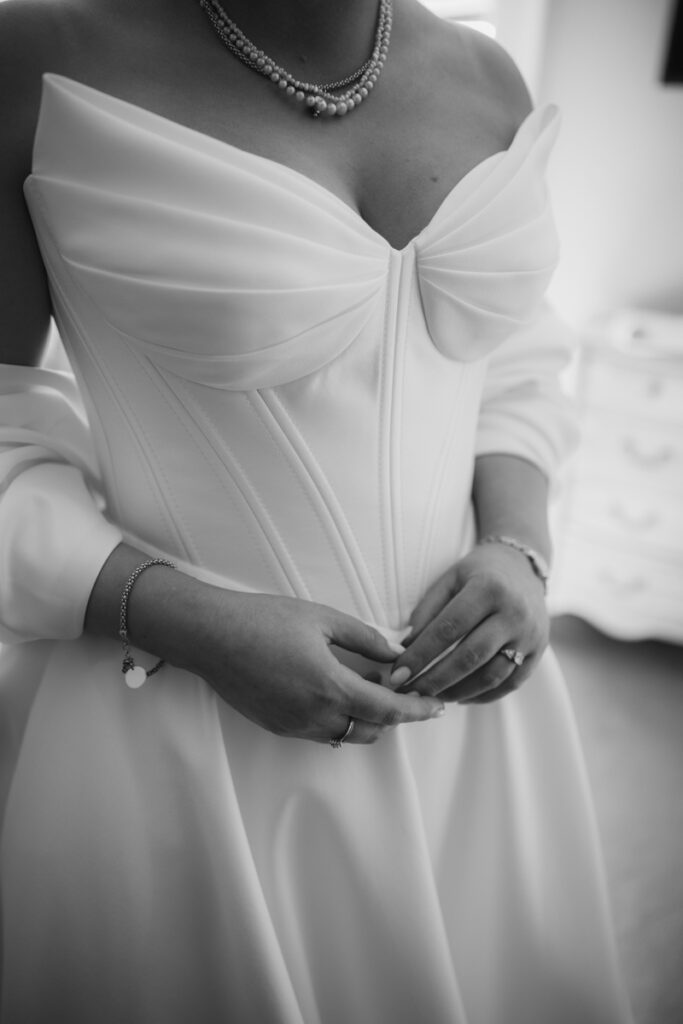 Elegant bride in a strapless wedding gown with pearl necklace, captured in relaxed documentary style.