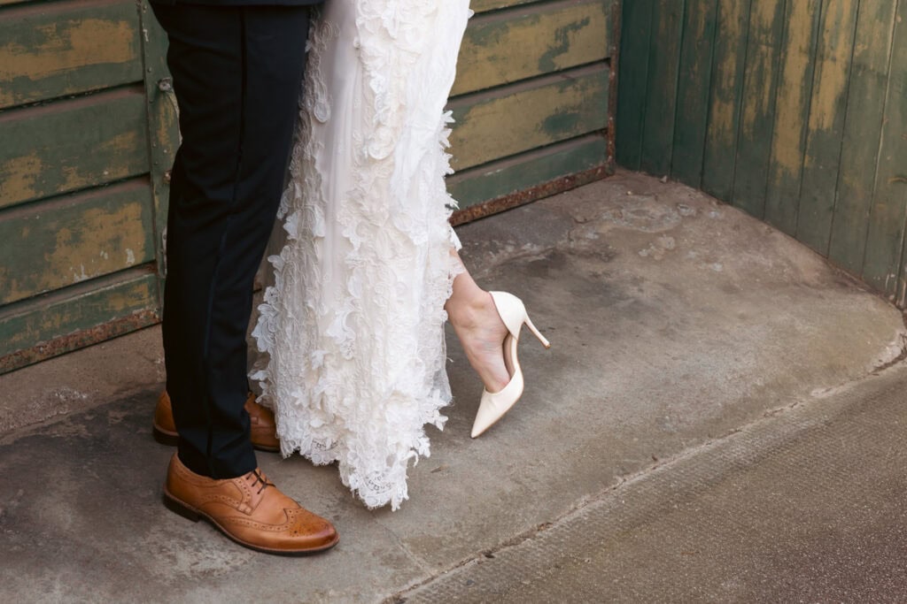 Close-up of bride and groom's feet, showcasing elegant wedding shoes and formal attire.
