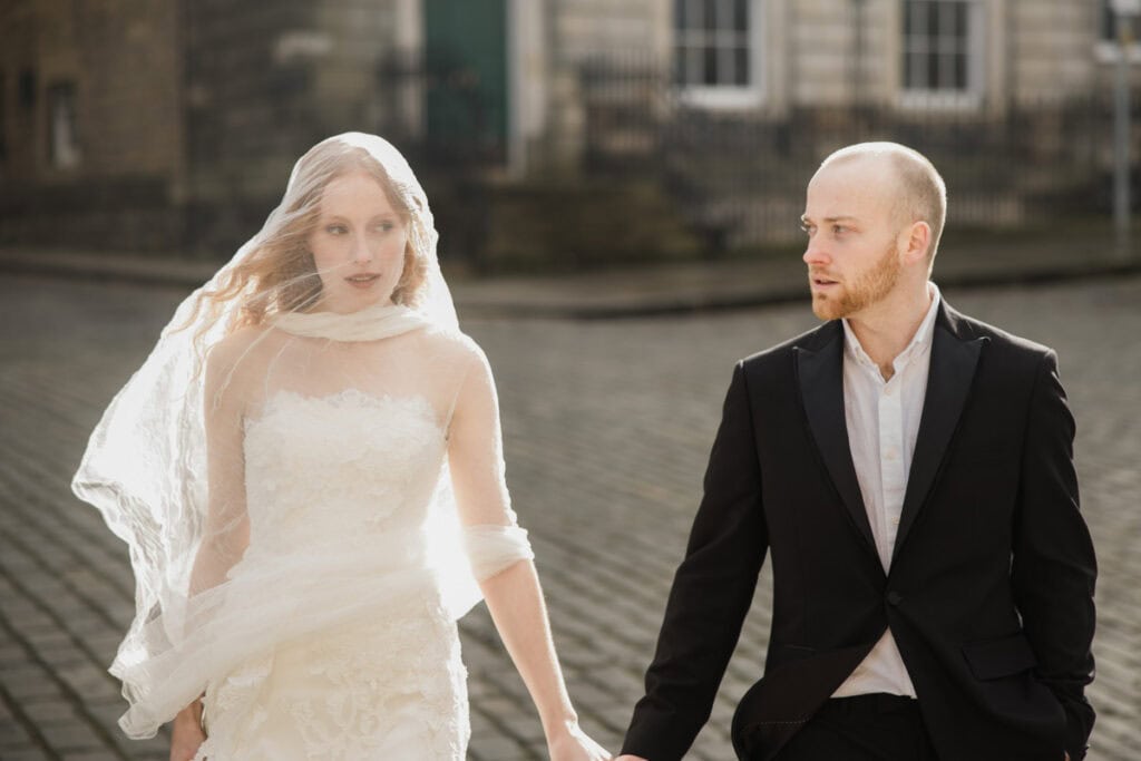 Romantic wedding couple in Scottish town, bride in lace dress and groom in suit.