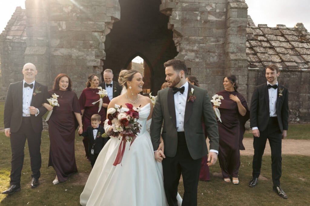Wedding couple walking with wedding party at Dunglass Estate in Scotland.