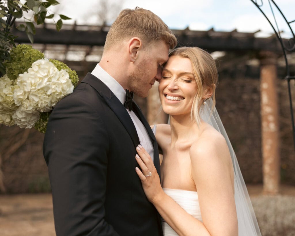 Bride and groom share a tender moment outdoors at their wedding.