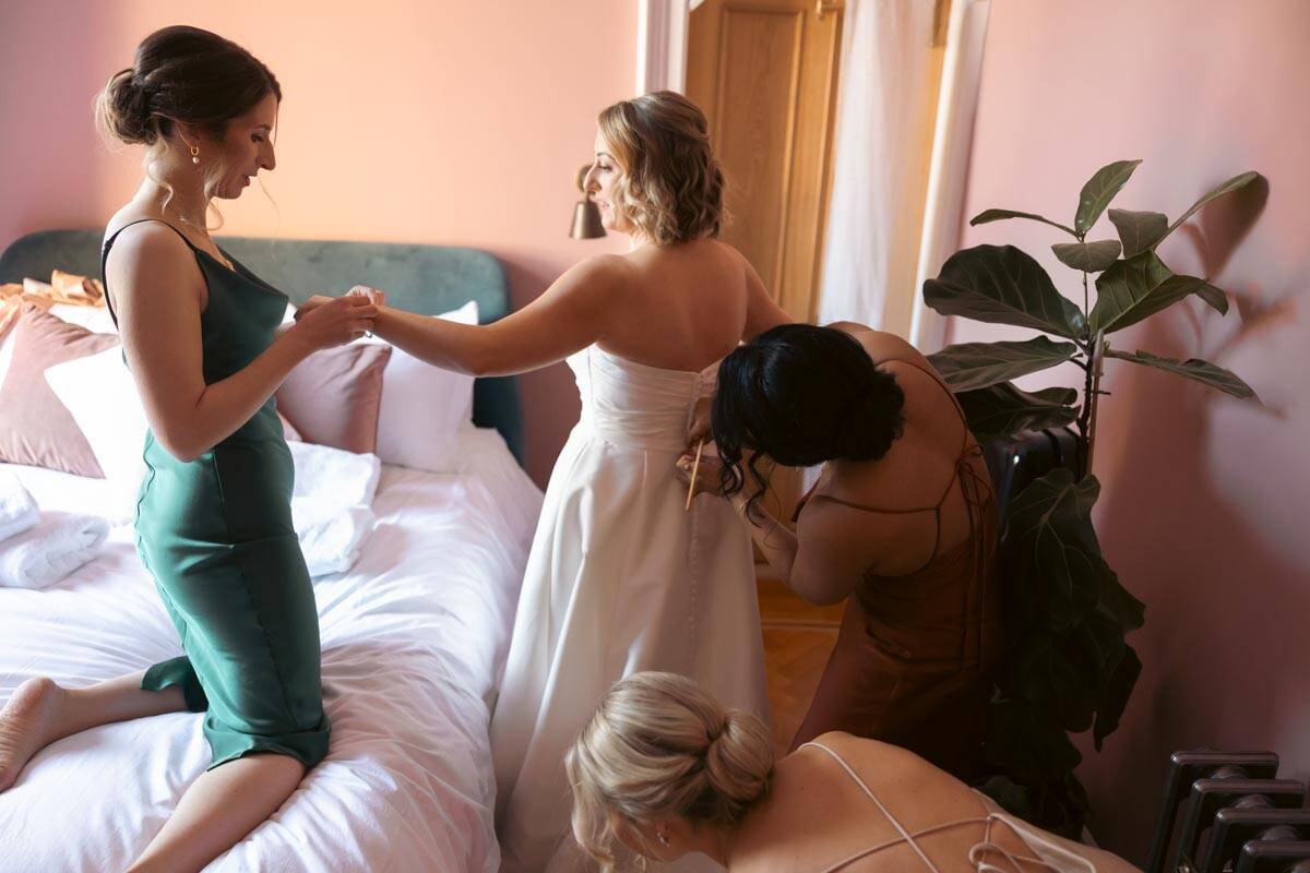 Bride getting ready with bridesmaids in a cozy Scottish bedroom.