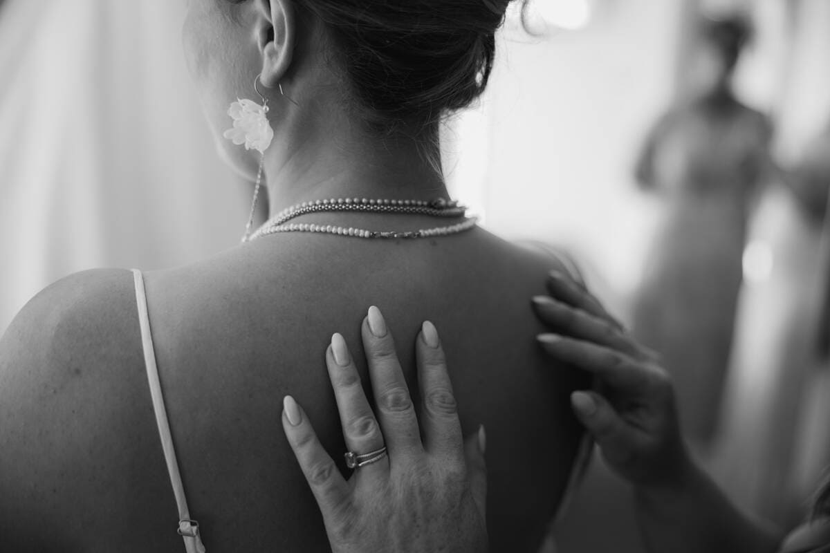 Close-up of bride's back with jewelry and wedding dress straps, black and white.