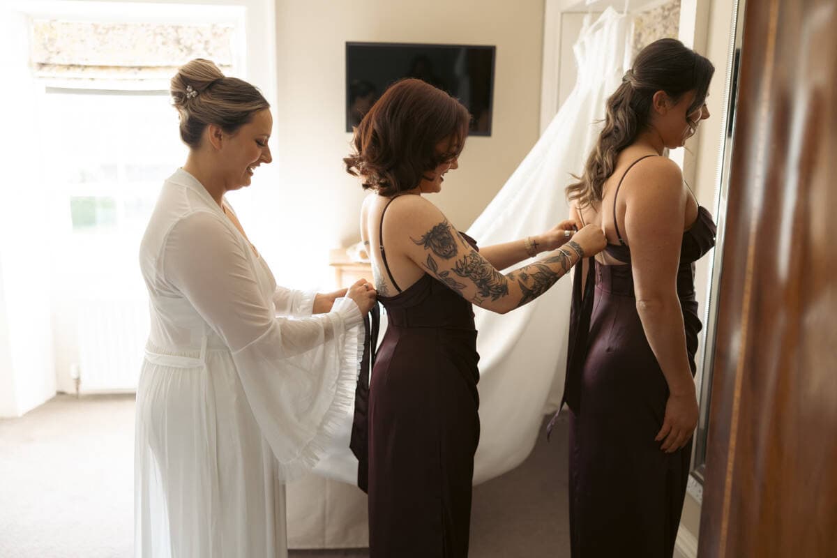 Bride helping bridesmaids get ready in a cozy Scottish home.