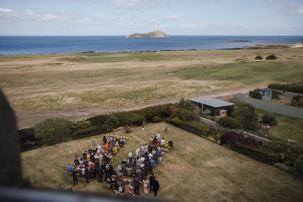 Wedding ceremony overlooking the Scottish coast with guests seated outdoors.