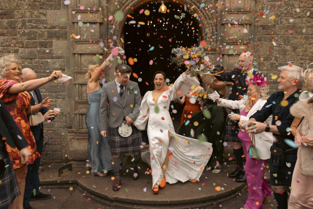 Bride and guests celebrating with confetti outside church.